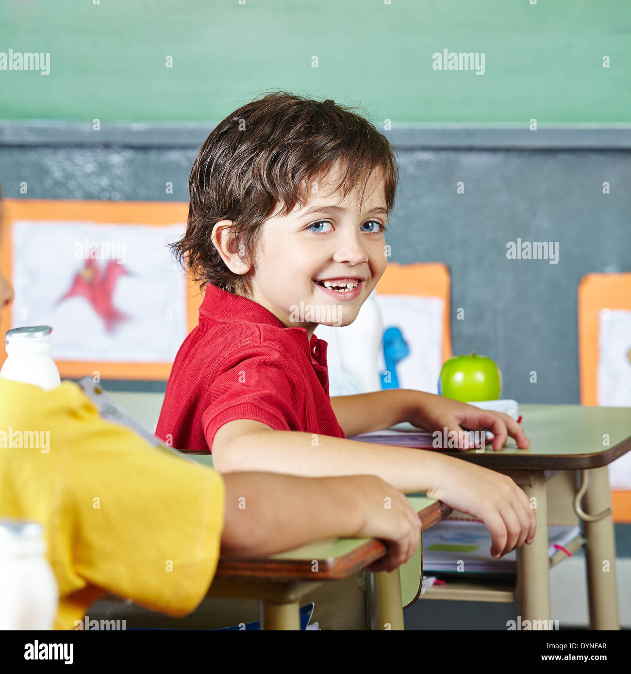 Glückliches abecedarian Kind sitzt lächelnd in Grundschule Unterricht Stockfoto