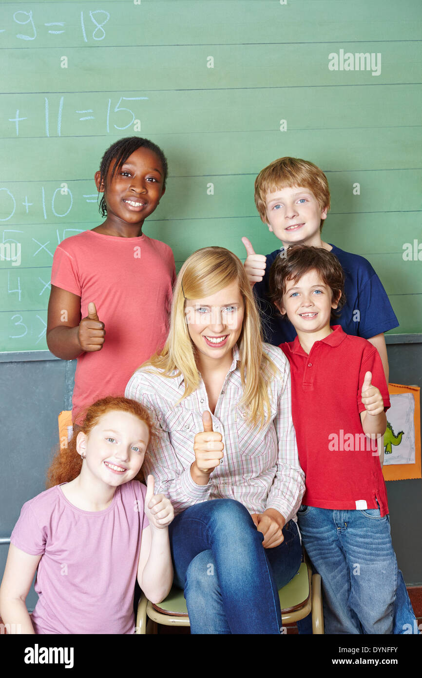 Glückliche Lehrer und Schüler, die Daumen hochhalten, in der Grundschule Stockfoto