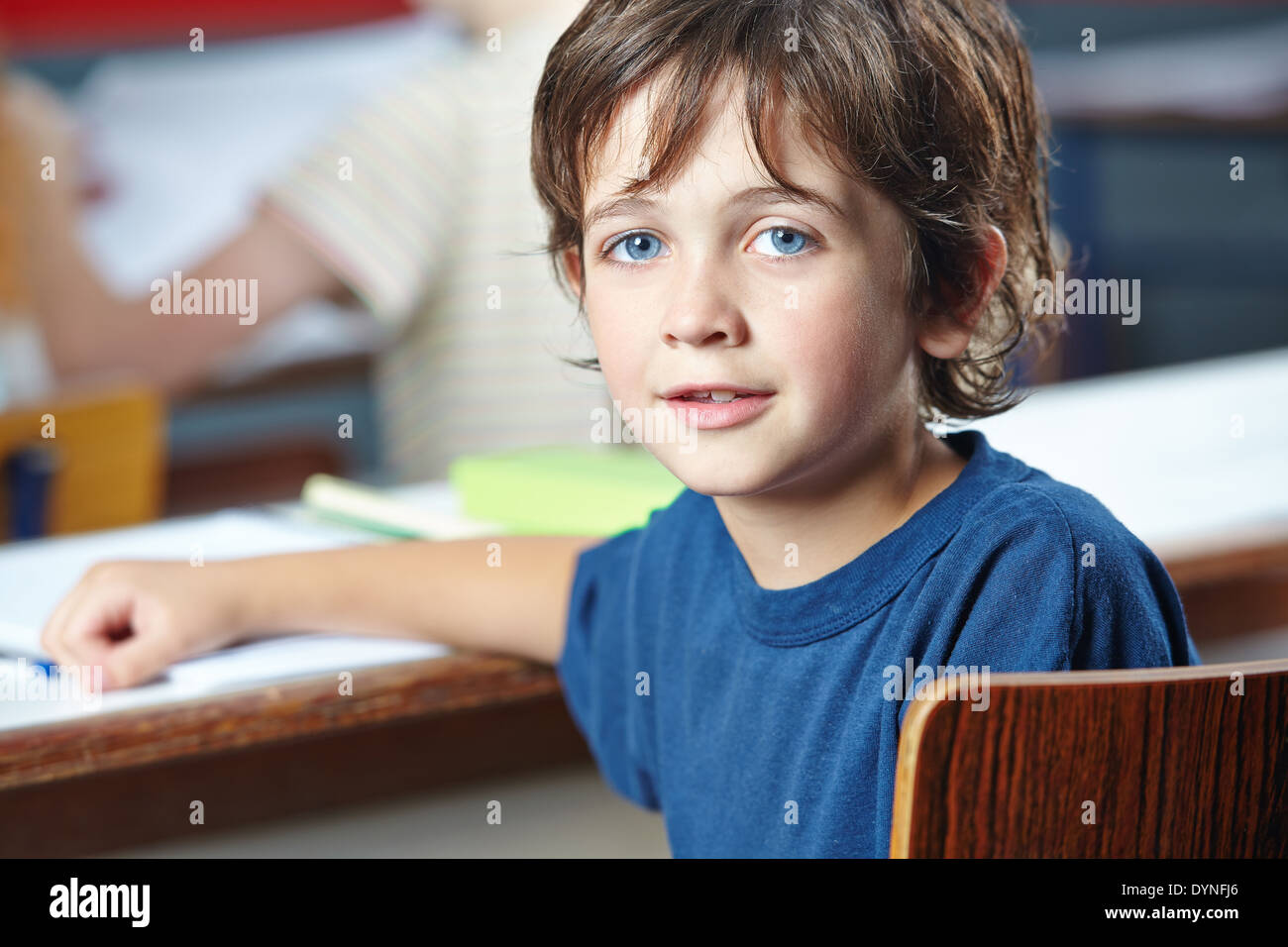 Lächelnde junge sitzt im Unterricht in der Grundschule Stockfoto