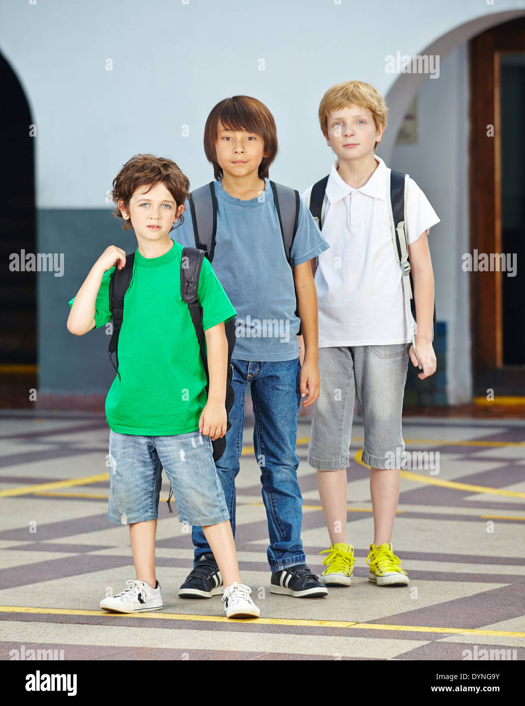 Drei Kinder in einer Reihe in der Grundschule auf einem Schulhof Stockfoto