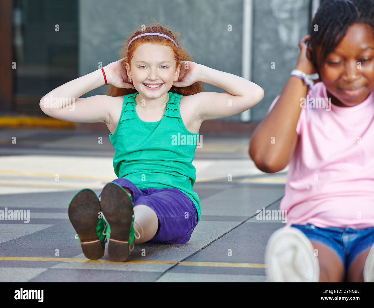Mädchen machen Sit-ups im Sportunterricht in der Grundschule Stockfoto