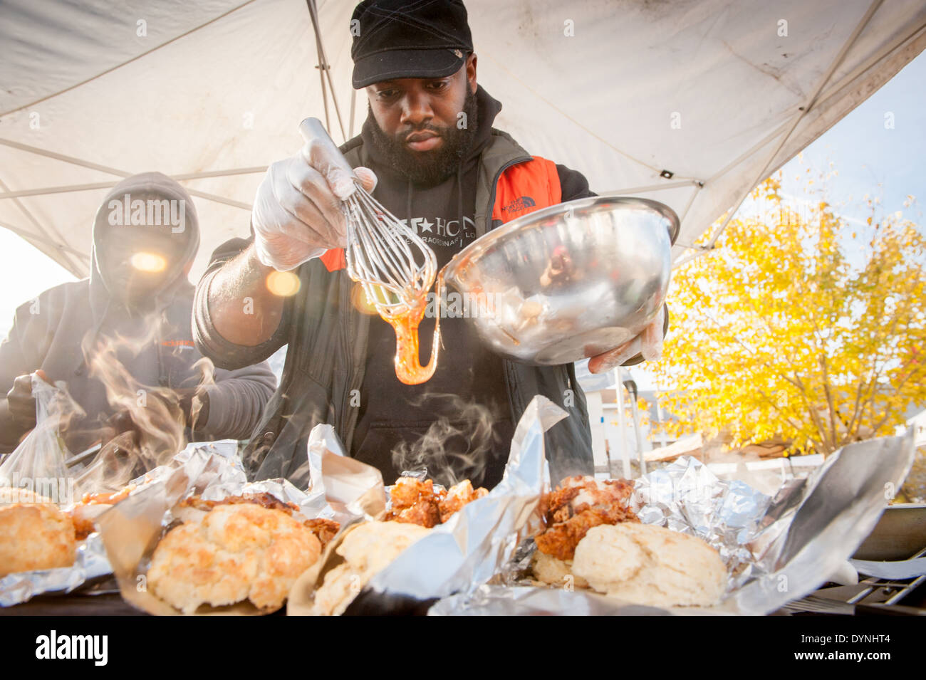 Markt-Verkäufer Gießen Sauce auf gebratenes Huhn auf dem Waverly Bauernmarkt in Baltimore, Maryland Stockfoto
