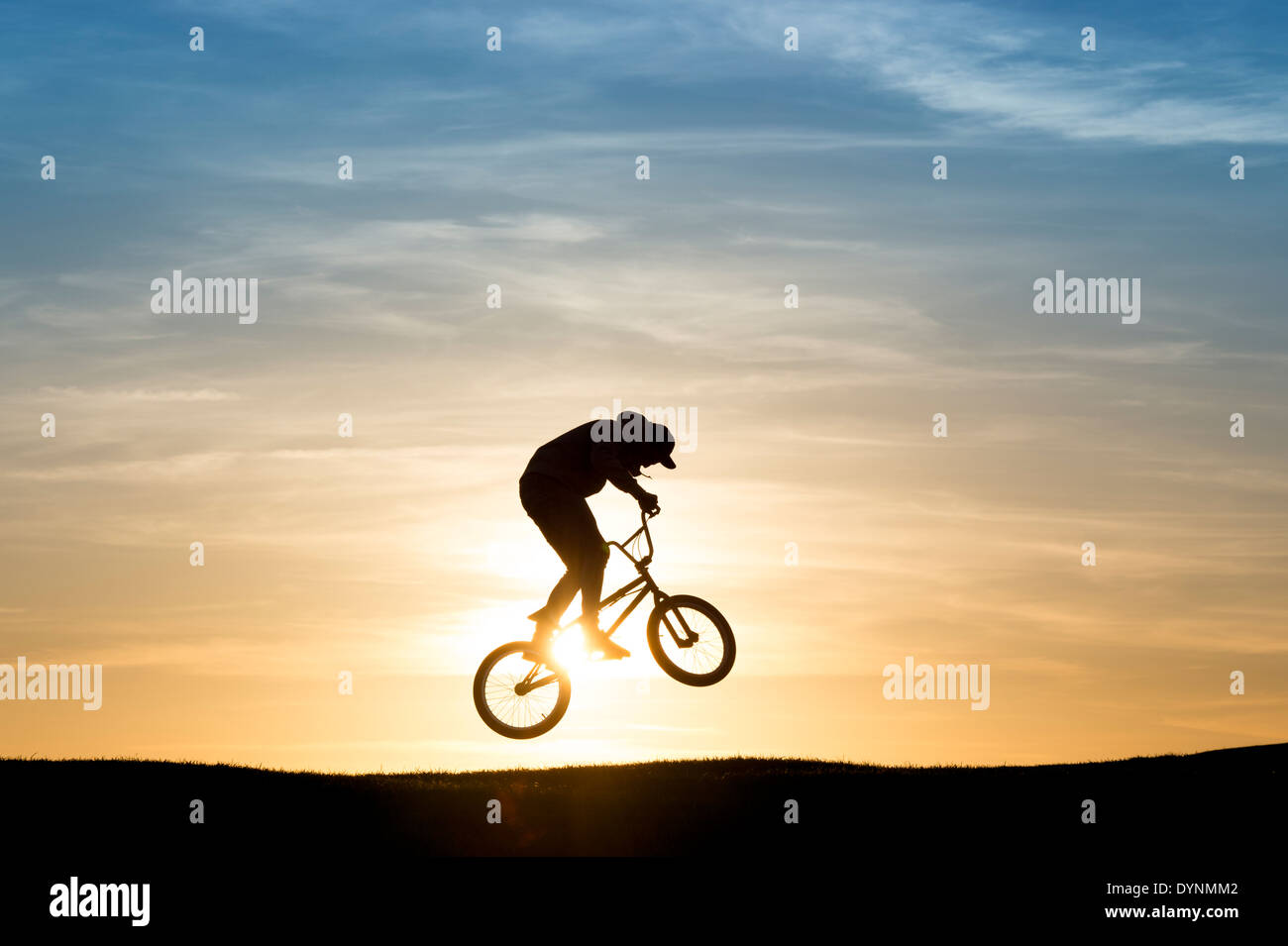 Junger Mann auf seinem BMX-Fahrrad in die Luft springen. Silhouette Stockfoto