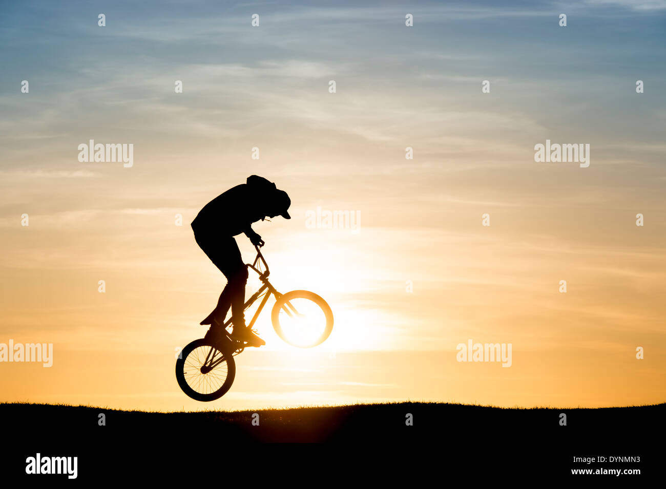 Junger Mann auf seinem BMX-Fahrrad in die Luft springen. Silhouette Stockfoto