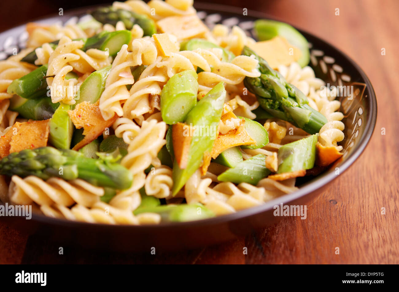 Pasta-Essen mit grünem Spargel, Veganer Aufschnitt und Knoblauchsauce Nussbaum. Stockfoto