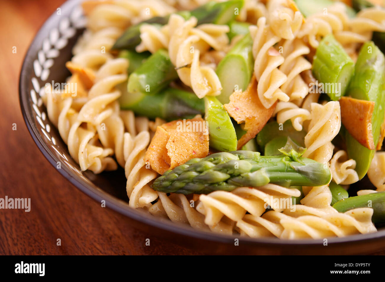 Pasta-Essen mit grünem Spargel, Veganer Aufschnitt und Knoblauchsauce Nussbaum. Stockfoto