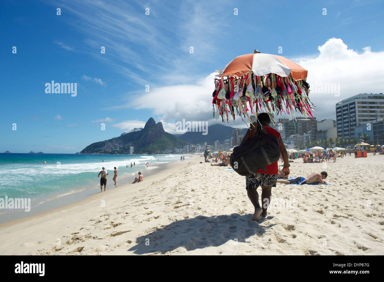 Strand-Anbieter verkaufen Bikini Badeanzüge zu Fuß entlang der Skyline von Ipanema Strand Rio de Janeiro Brasilien Stockfoto