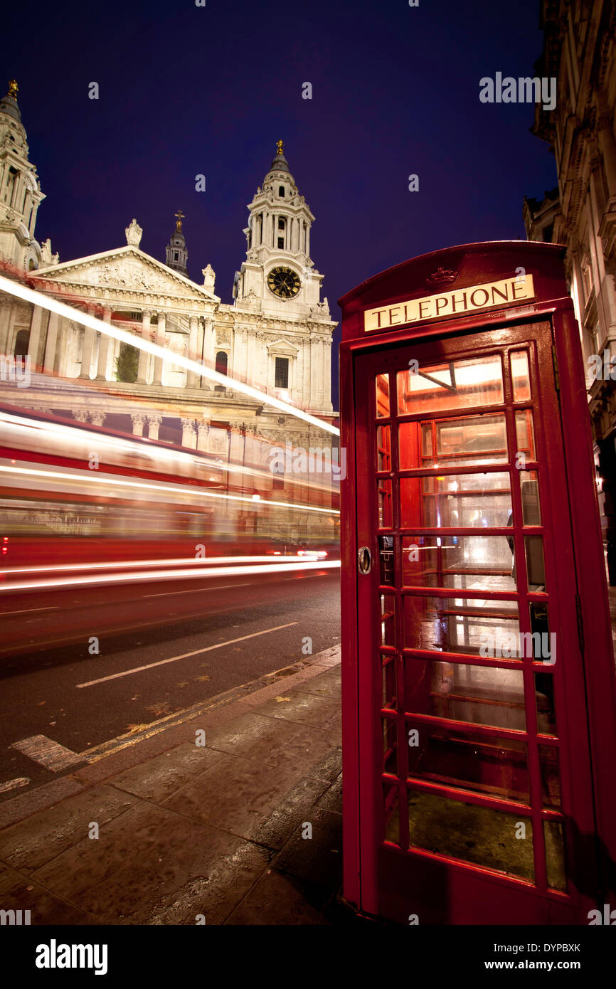 Einem roten Bus vorbei an St. Pauls Cathedral, London, in der Dämmerung, mit typischen roten Phonebox im Vordergrund zu beschleunigen. Im Hochformat. Stockfoto