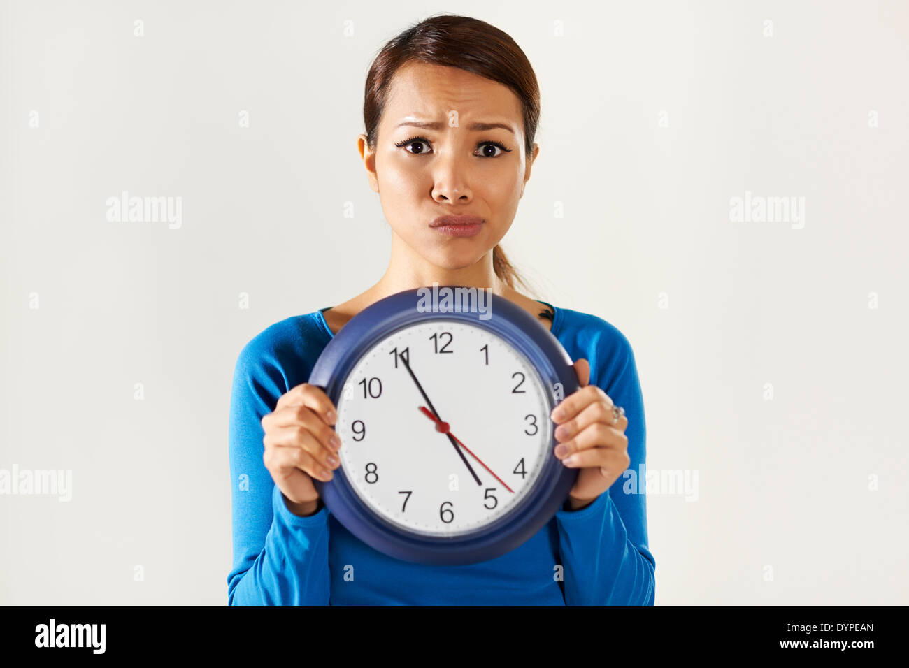 Porträt von asiatischen Geschäftsfrau hält große blaue Armbanduhr und Blick in die Kamera mit Sorge Ausdruck Stockfoto