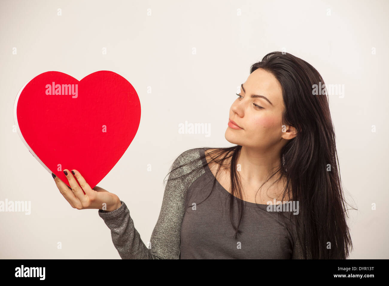 Mädchen hält über große herzförmige Schachtel mit Süßigkeiten für den Valentinstag Stockfoto