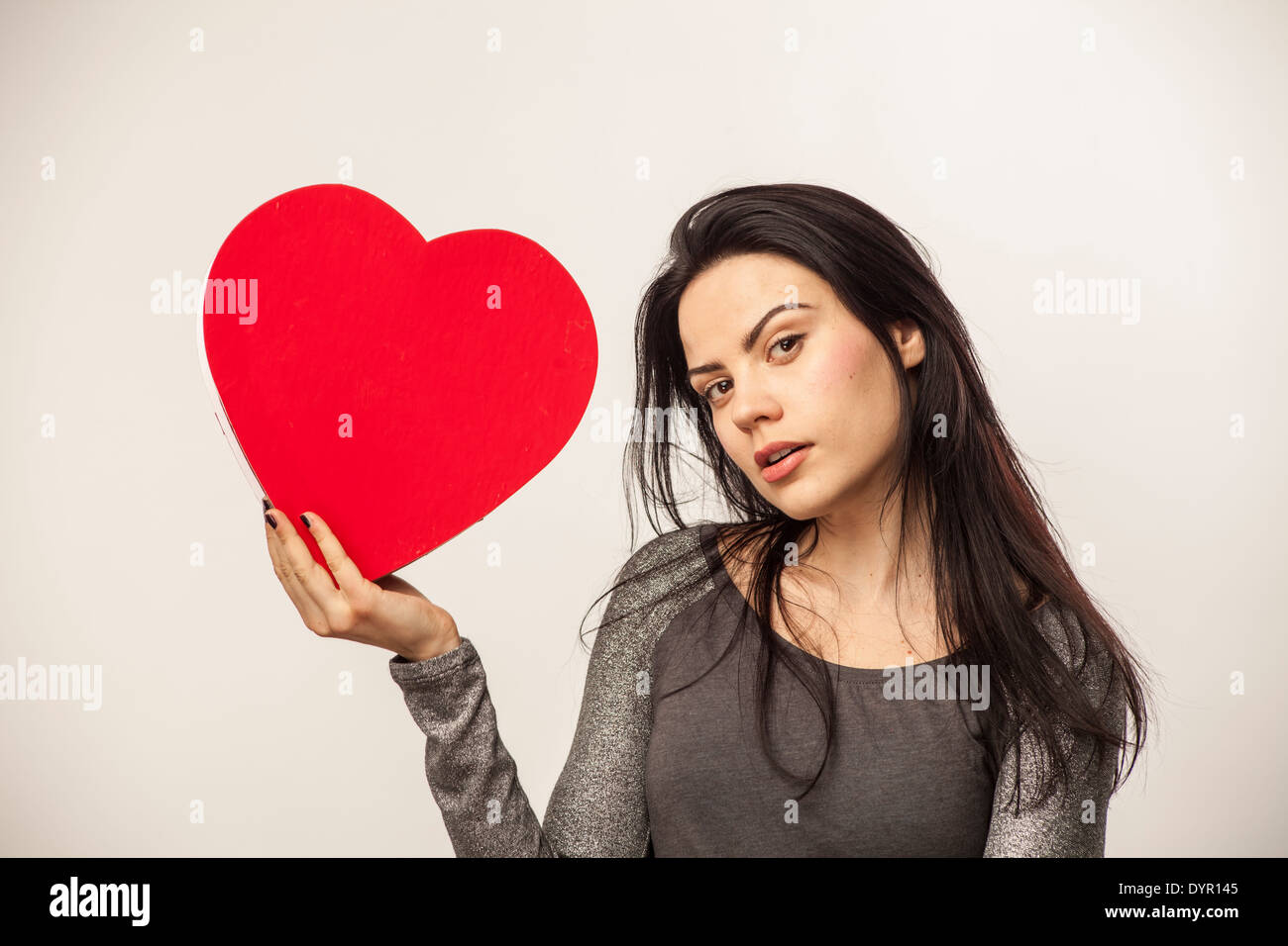 Mädchen hält über große herzförmige Schachtel mit Süßigkeiten für den Valentinstag Stockfoto