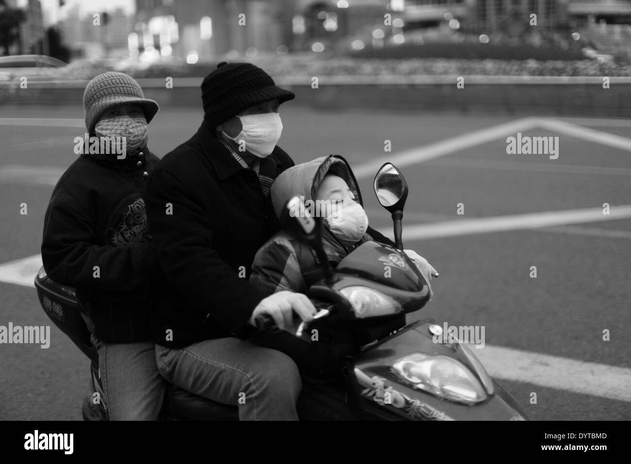 Drei Menschen tragen Masken Fahrt auf einem Motorrad auf einer Straße Stockfoto