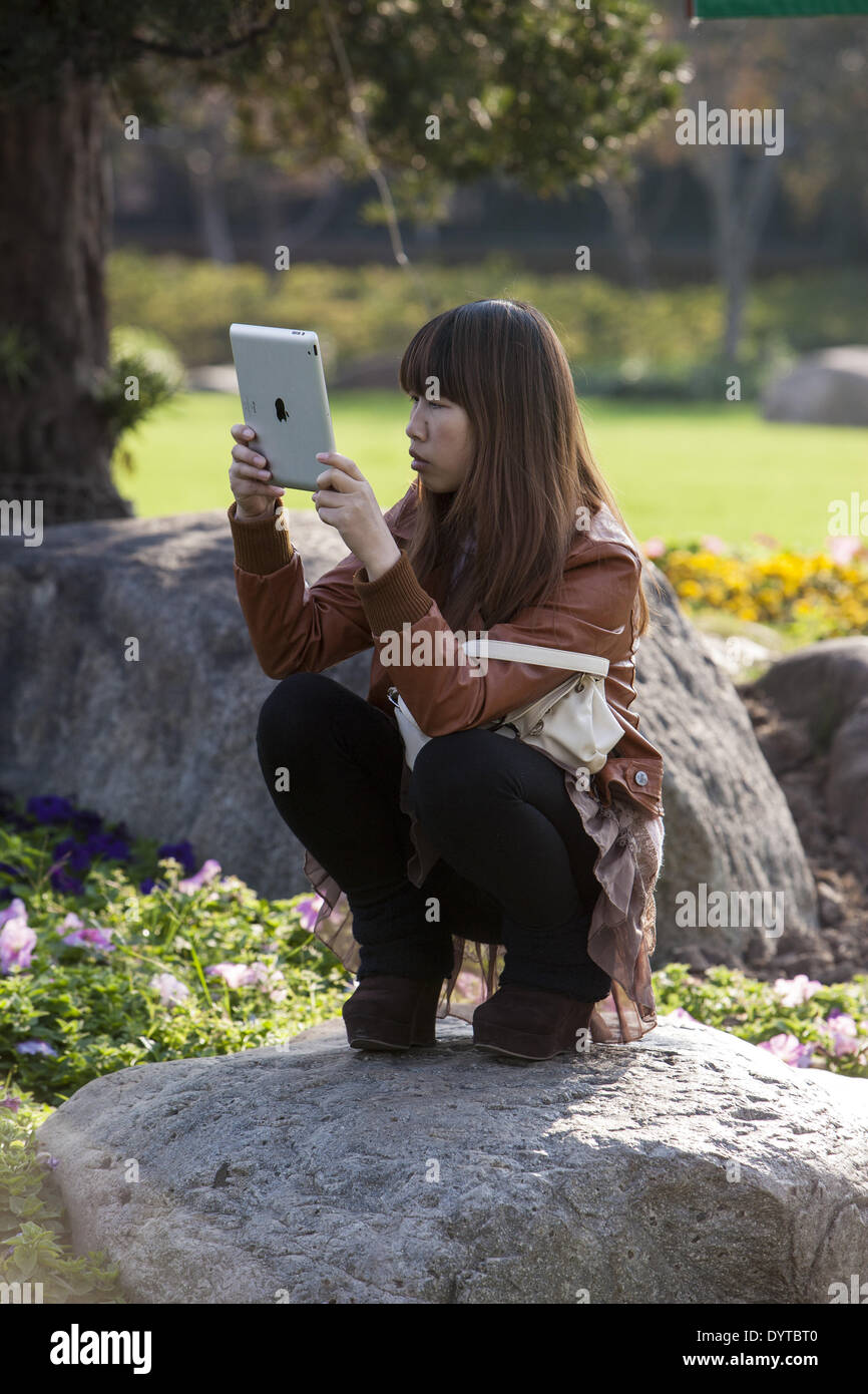 Eine Frau benutzt eine Ipad, ein Bild in einem park Stockfoto