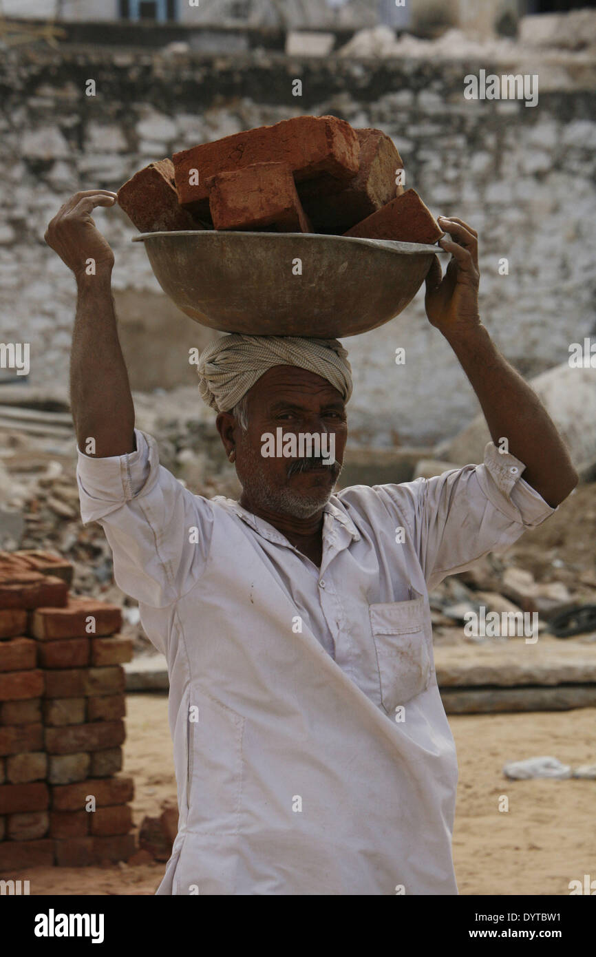 Eine Mann tragen trägt Ziegel auf einer Baustelle in Pushkar Stadt Stockfoto