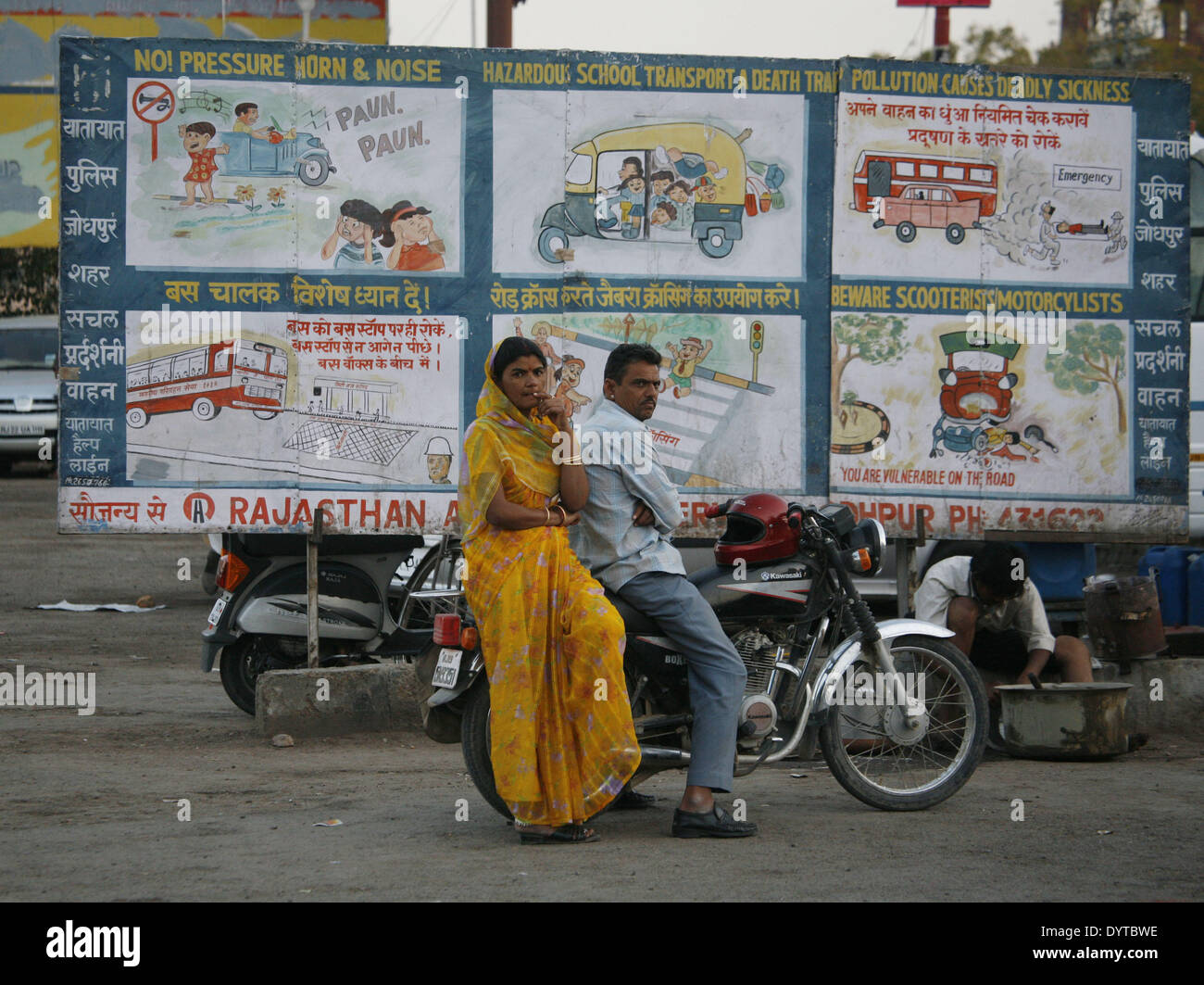 Ein paar sitzen auf einem Motorrad vor einer Plakatwand mit Sicherheit im Straßenverkehr in Jodhpur Stadt Stockfoto
