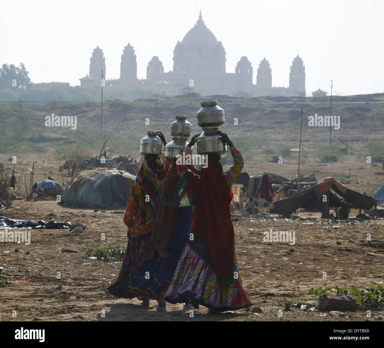 Frauen tragen Wasser auf ihrem Kopf Weg zurück in ihre Heimat (Zelt) mit Umaid-Bhavan-Palast im Hintergrund in Jodhpur Stadt Stockfoto