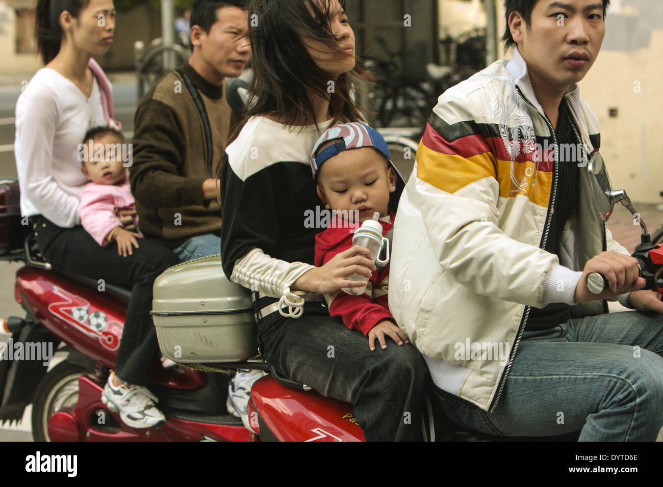 2 Paare tragen, die ihre Kinder auf ihren Motorrädern auf einer Straße in Shanghai am 10. Okt 07 fahren Stockfoto