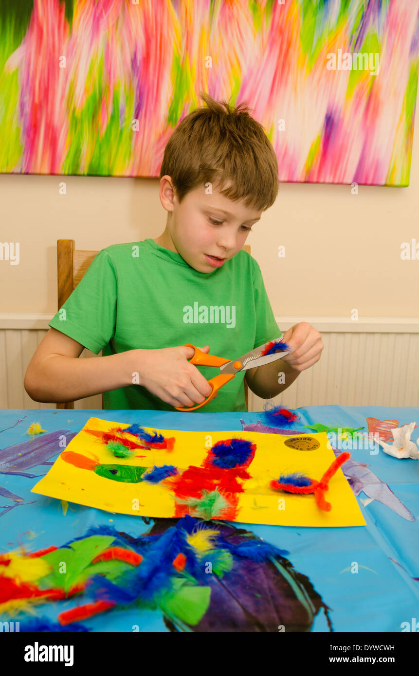 acht Jahre alter Junge Kunst und Handwerk Montage mit Klebstoff Schere und Farbe zu tun. Stockfoto