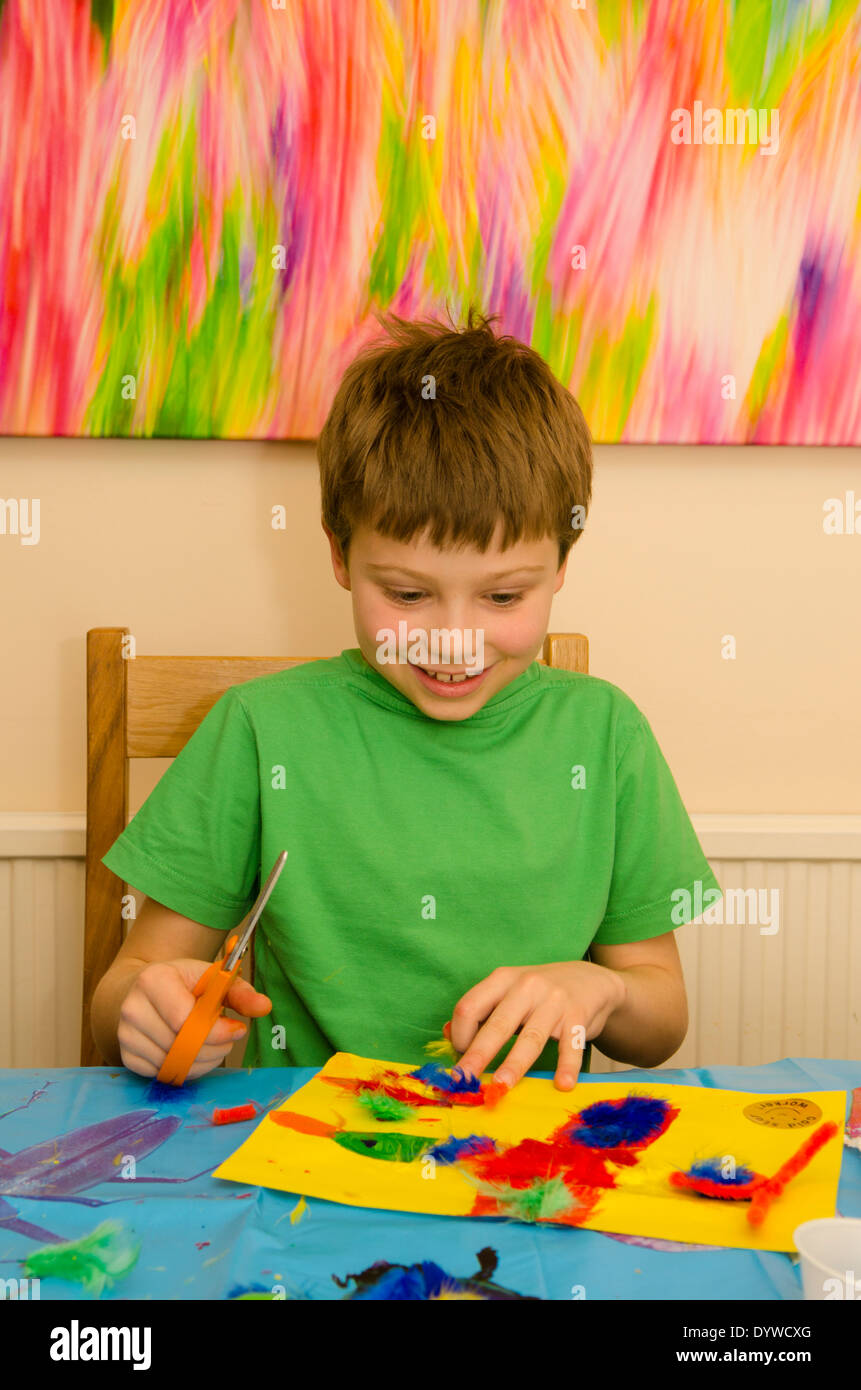 acht Jahre alter Junge Kunst und Handwerk Montage mit Klebstoff Schere und Farbe zu tun. Stockfoto