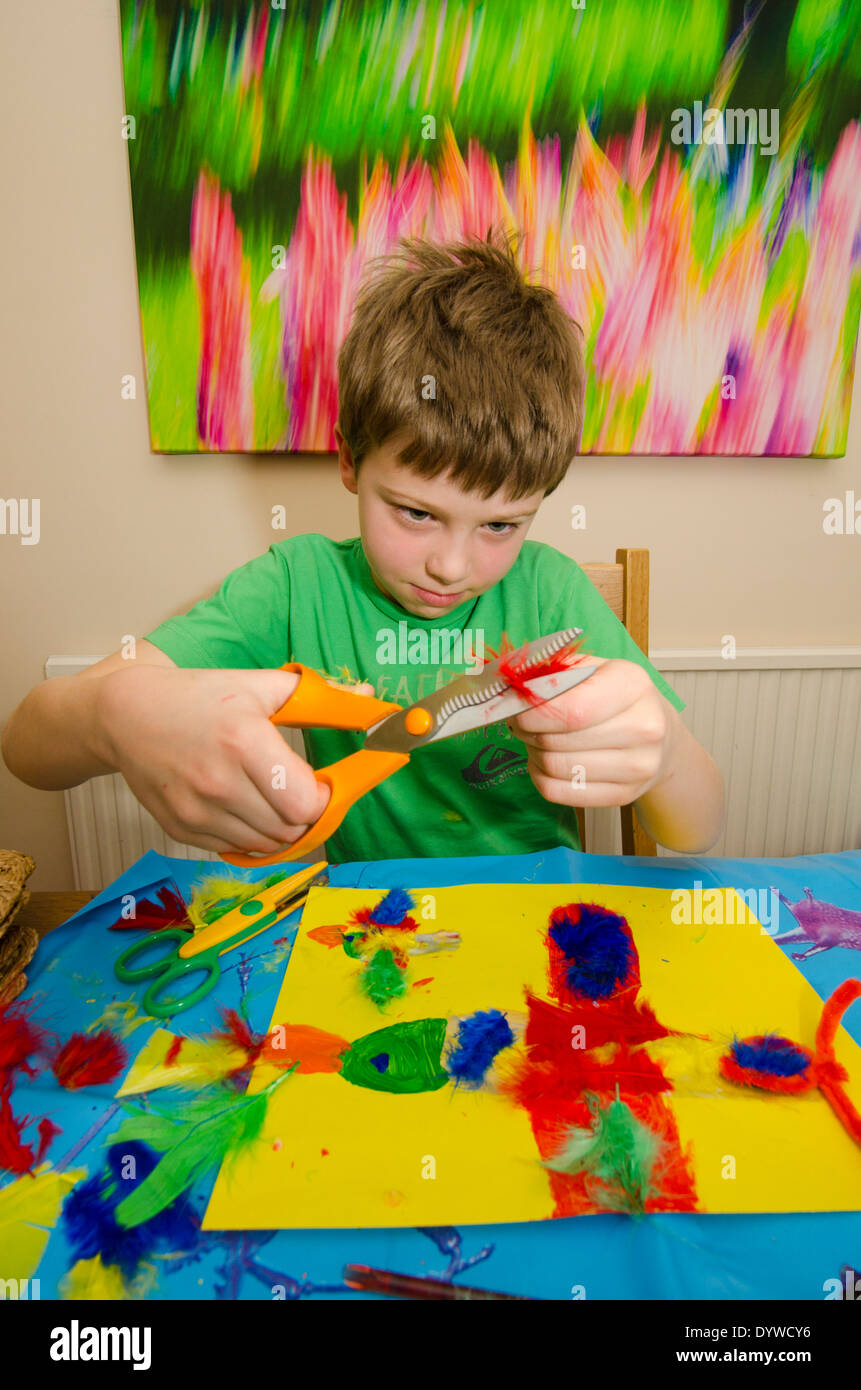 acht Jahre alter Junge Kunst und Handwerk Montage mit Klebstoff Schere und Farbe zu tun. Stockfoto