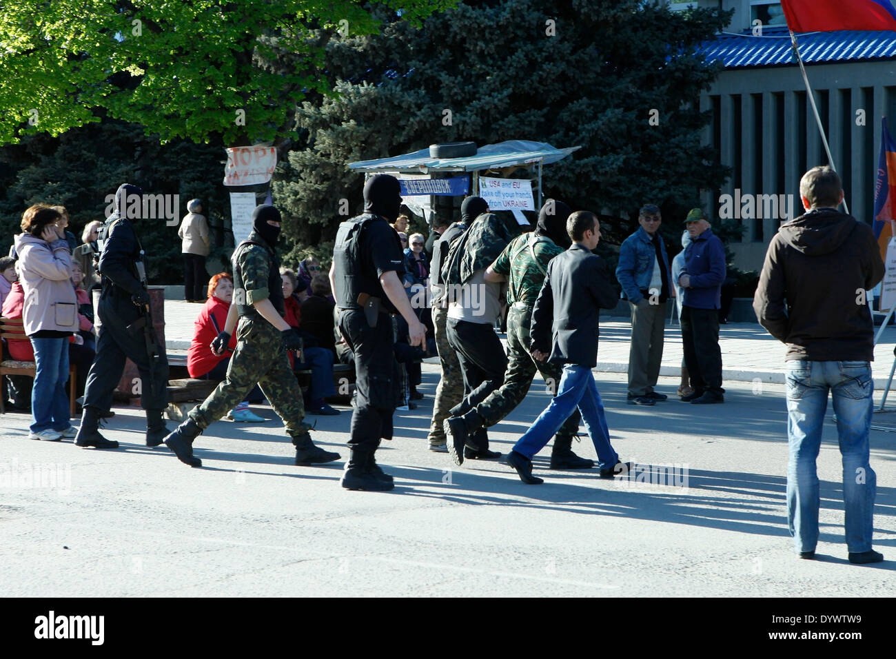 eine Gruppe bewaffnete und maskierte Männer bringen einen vermummten Mann zum Geheimdienst Bürogebäude in Luhansk. Stockfoto