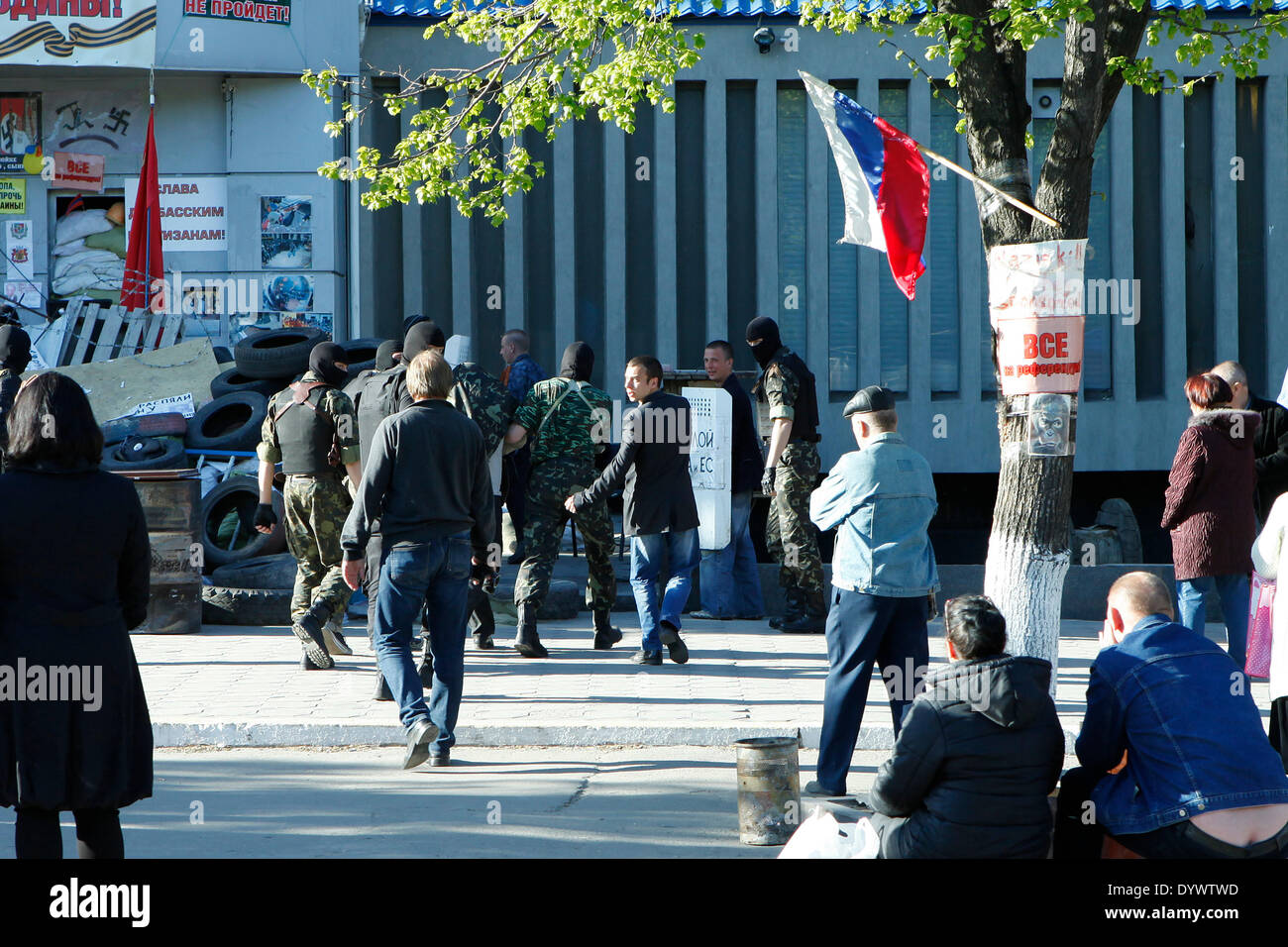 eine Gruppe bewaffnete und maskierte Männer bringen einen vermummten Mann zum Geheimdienst Bürogebäude in Luhansk. Stockfoto