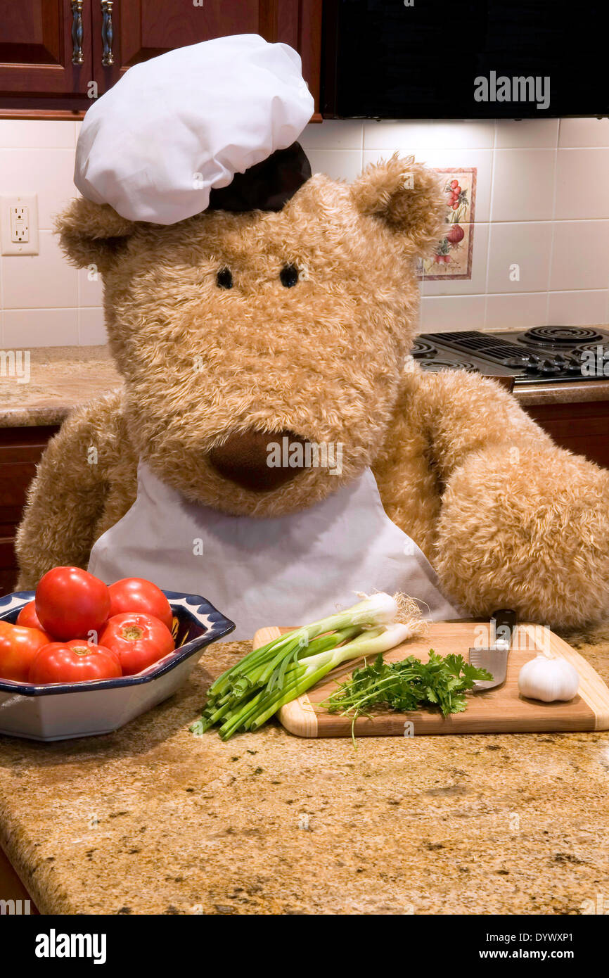 Überdimensionierte Teddybär gekleidet in Schürze und Hut des Küchenchefs in der Küche. Stockfoto