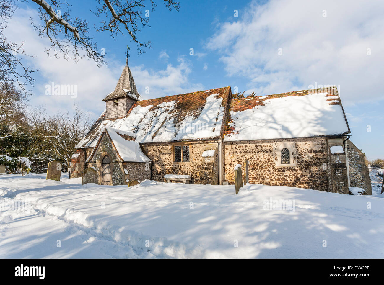 Kirche des Heiligen Nikolaus, Pyrford, Surrey, UK im Schnee im Winter bei Sonnenschein mit blauem Himmel Stockfoto