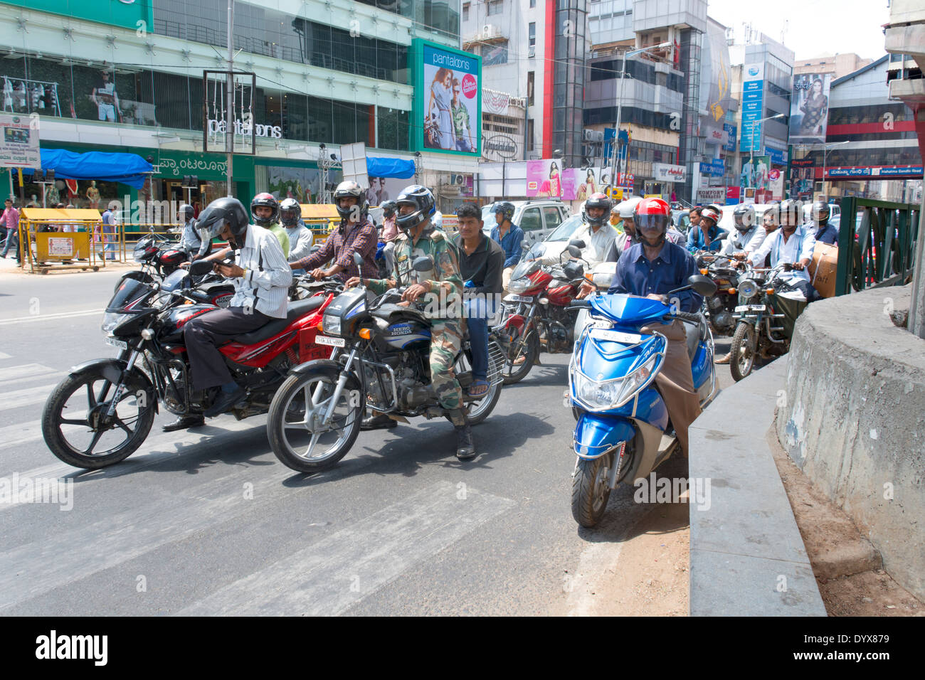 Eine Straße Szene zeigt Menschen auf Motorrädern durch die u-Bahnstation MG (Mahatma Gandhi) unterwegs in Bangalore, Karnataka, Indien Stockfoto