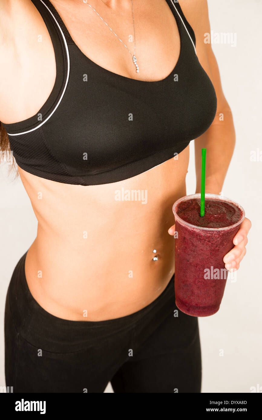 Frau hält einen Berry Frucht Smoothie Taille Ebene zeigt gesunden schlanken Körper Stockfoto