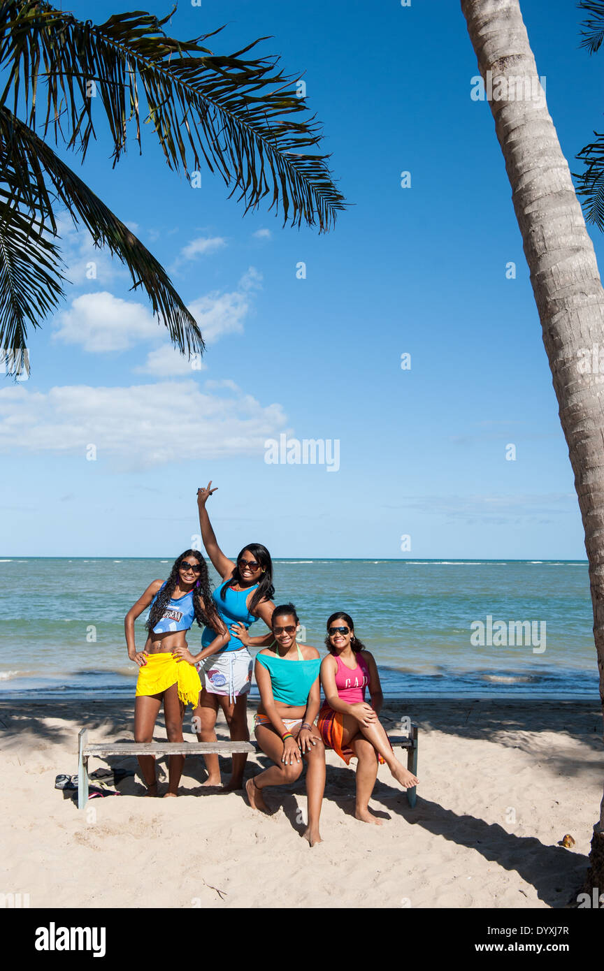 Itaparica Island, Bundesstaat Bahia, Brasilien. Vier junge Frauen, alle Formen und Größen, mit Sonnenbrille am Strand lächelnd. Stockfoto