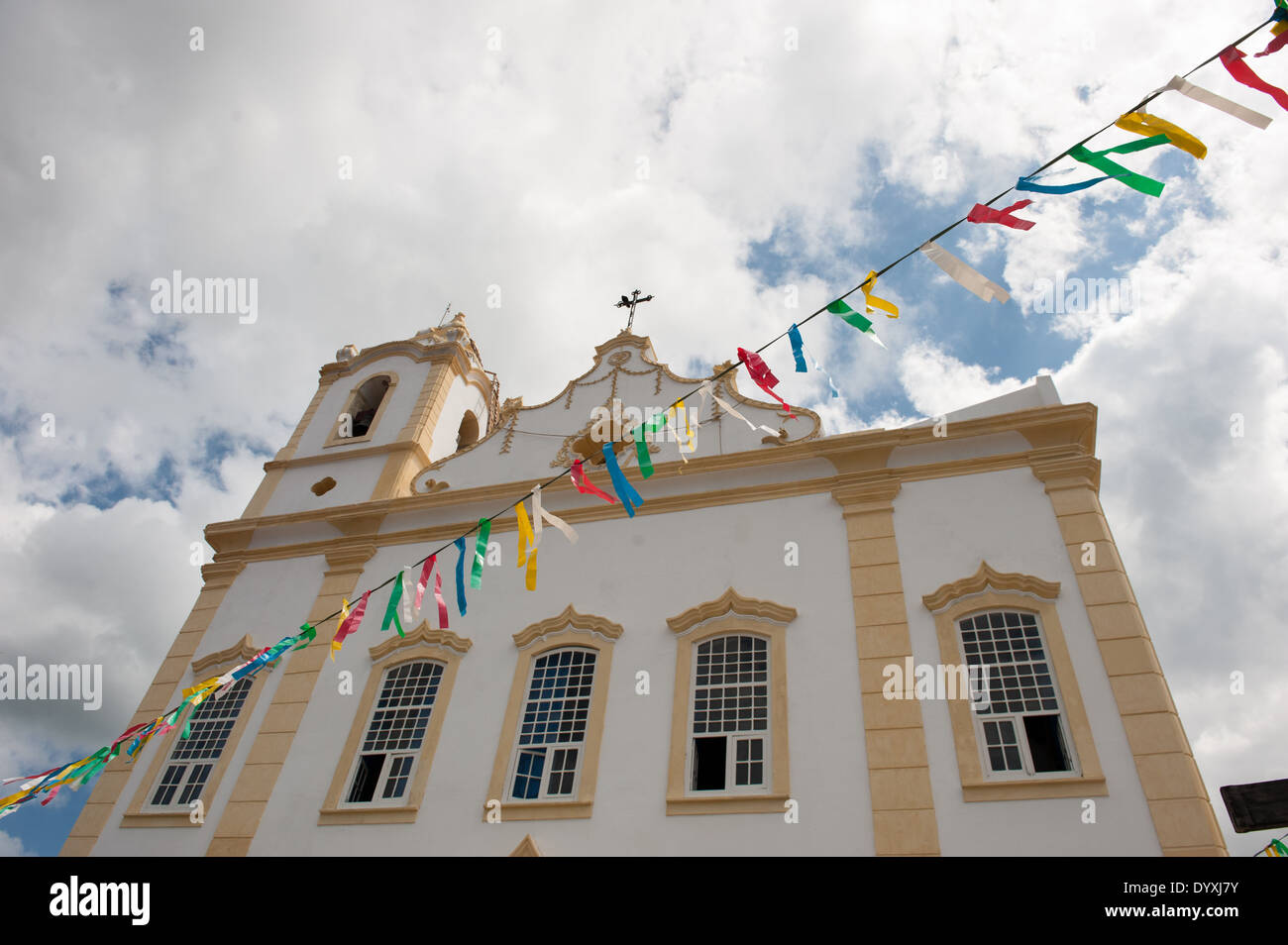 Itaparica Island, Bundesstaat Bahia, Brasilien. Itaparica-Stadt. Restaurierte Kolonialzeit Barockkirche, bunte Girlande. Blauer Himmel und weiße Wolken. Stockfoto