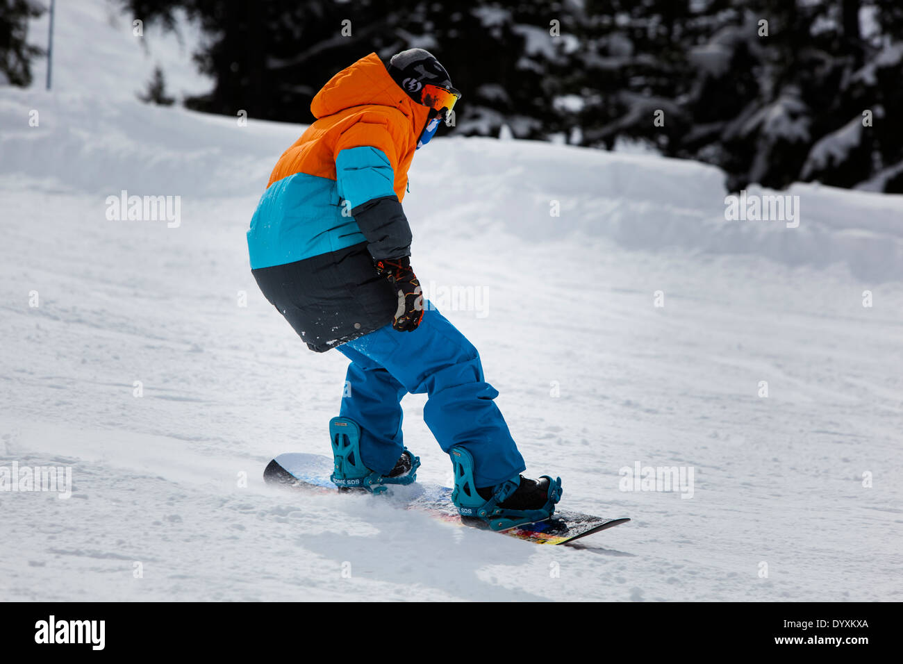 Snowboarder mit bunten Jacke und orange reflektierende Schutzbrillen, senkt sich die Piste. Stockfoto