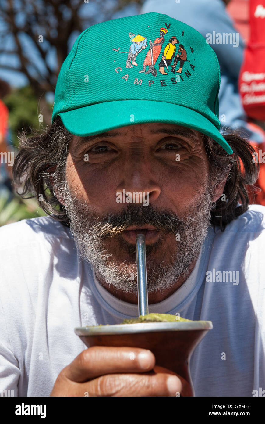 Brasilia, Brasilien. Bärtige Demonstrator von Via Campesina Bewegung mit einer Via Campesina Baseball-Kappe aus einem Chimarrao Mate-Tee trinken. Stockfoto