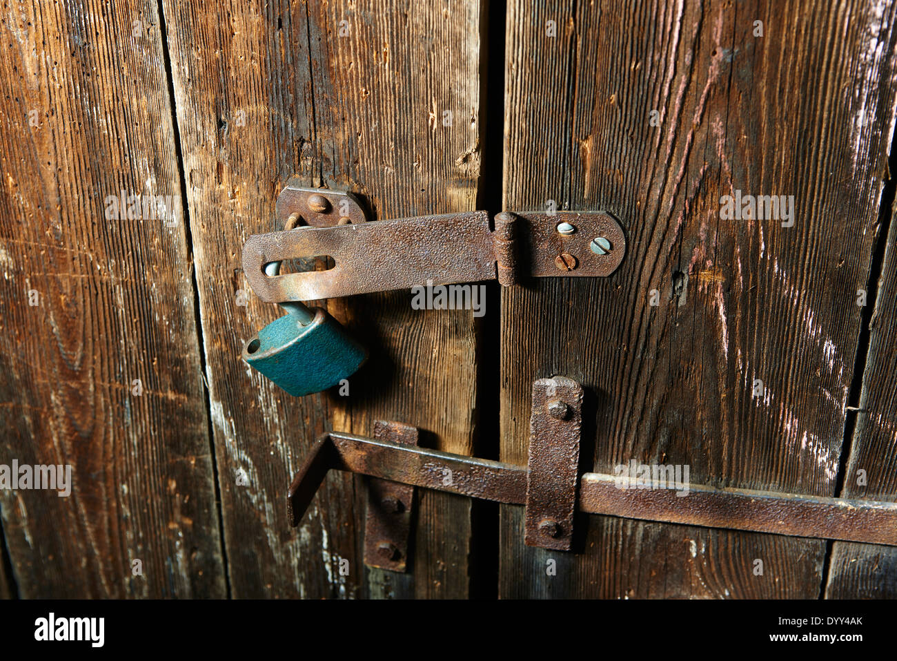 Nahaufnahme eines Vorhängeschlosses und altes Metall Hasp und Heften auf einer alten Holztür Stockfoto