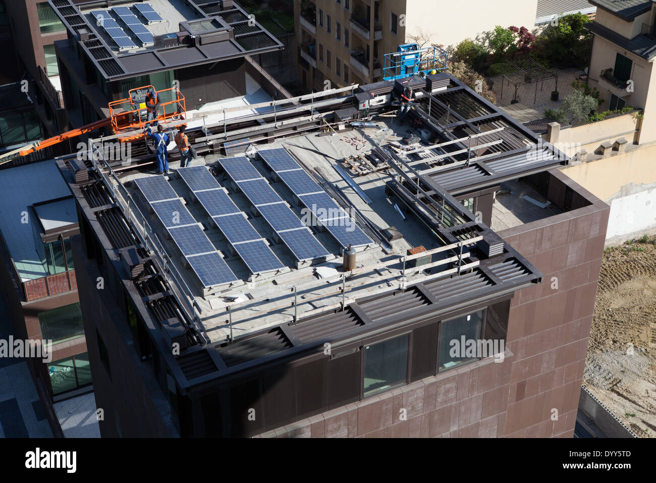 Die Arbeiter platzieren Fotovoltaikanlagen auf dem Dach eines Gebäudes. Mailand, Italien Stockfoto