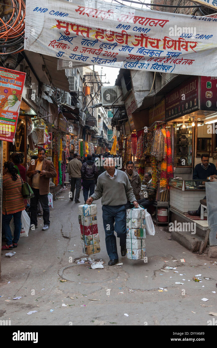 Neu-Delhi, Indien. Schmale Straße auf dem Markt, Chandni Chowk Bereich. Devanagari-Skript auf dem Overhead Banner. Stockfoto