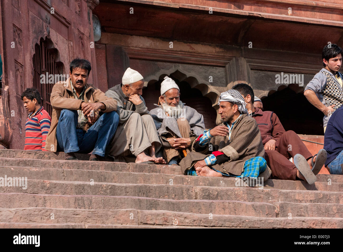 Neu-Delhi, Indien. Muslimische Männer sitzen auf den Stufen der Jama Masjid (Freitagsmoschee) Gebetszeit warten. Stockfoto