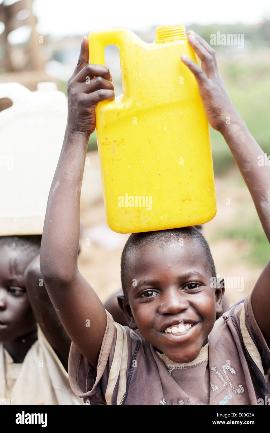 Kinder sammeln Wasser aus einer unreinen Regierung Wasserquelle in den Kosovo Slumviertel der Stadt Kampala in Uganda. Stockfoto
