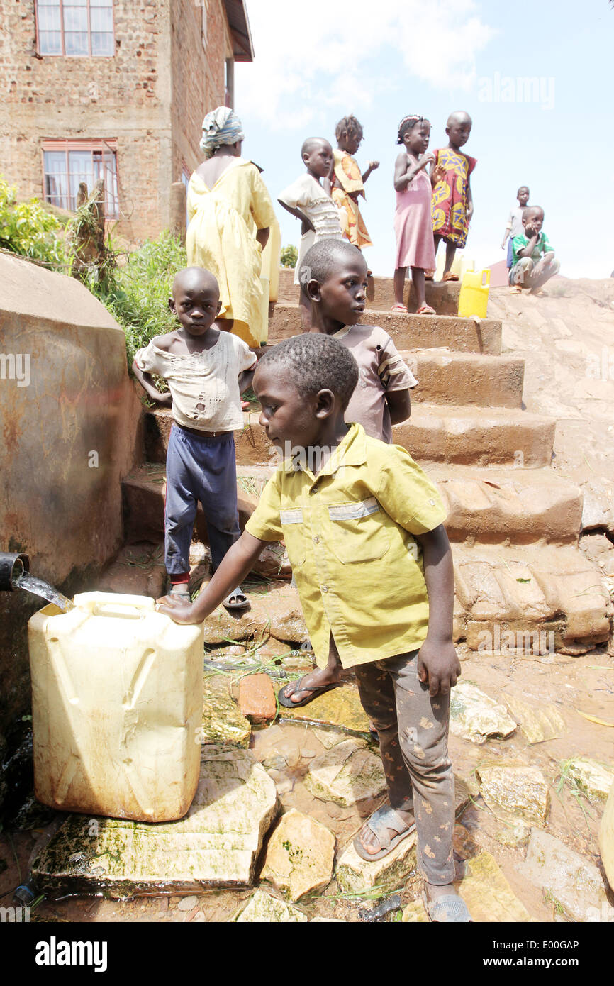 Kinder sammeln Wasser aus einer unreinen Regierung Wasserquelle in den Kosovo Slumviertel der Stadt Kampala in Uganda. Stockfoto
