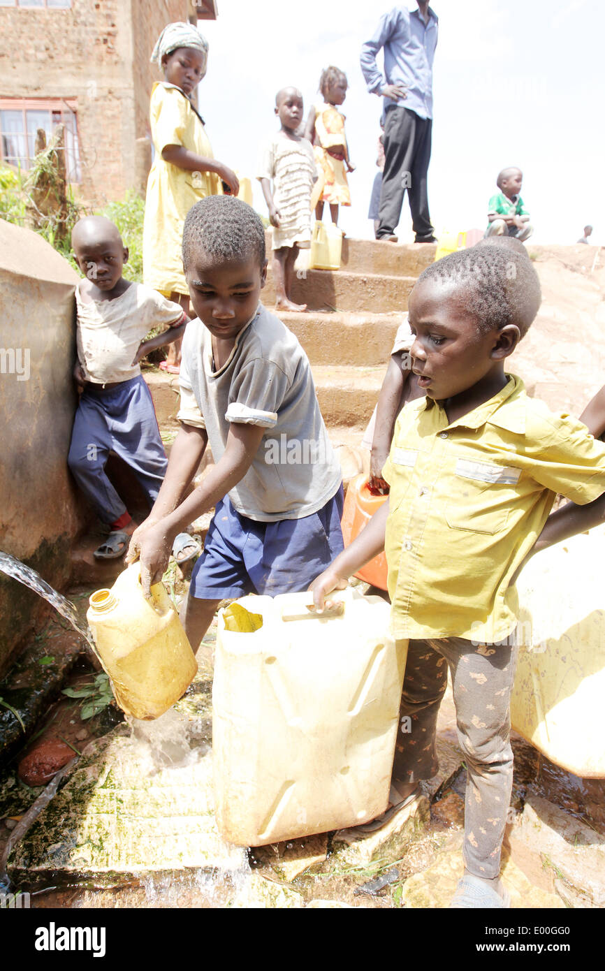 Kinder sammeln Wasser aus einer unreinen Regierung Wasserquelle in den Kosovo Slumviertel der Stadt Kampala in Uganda. Stockfoto