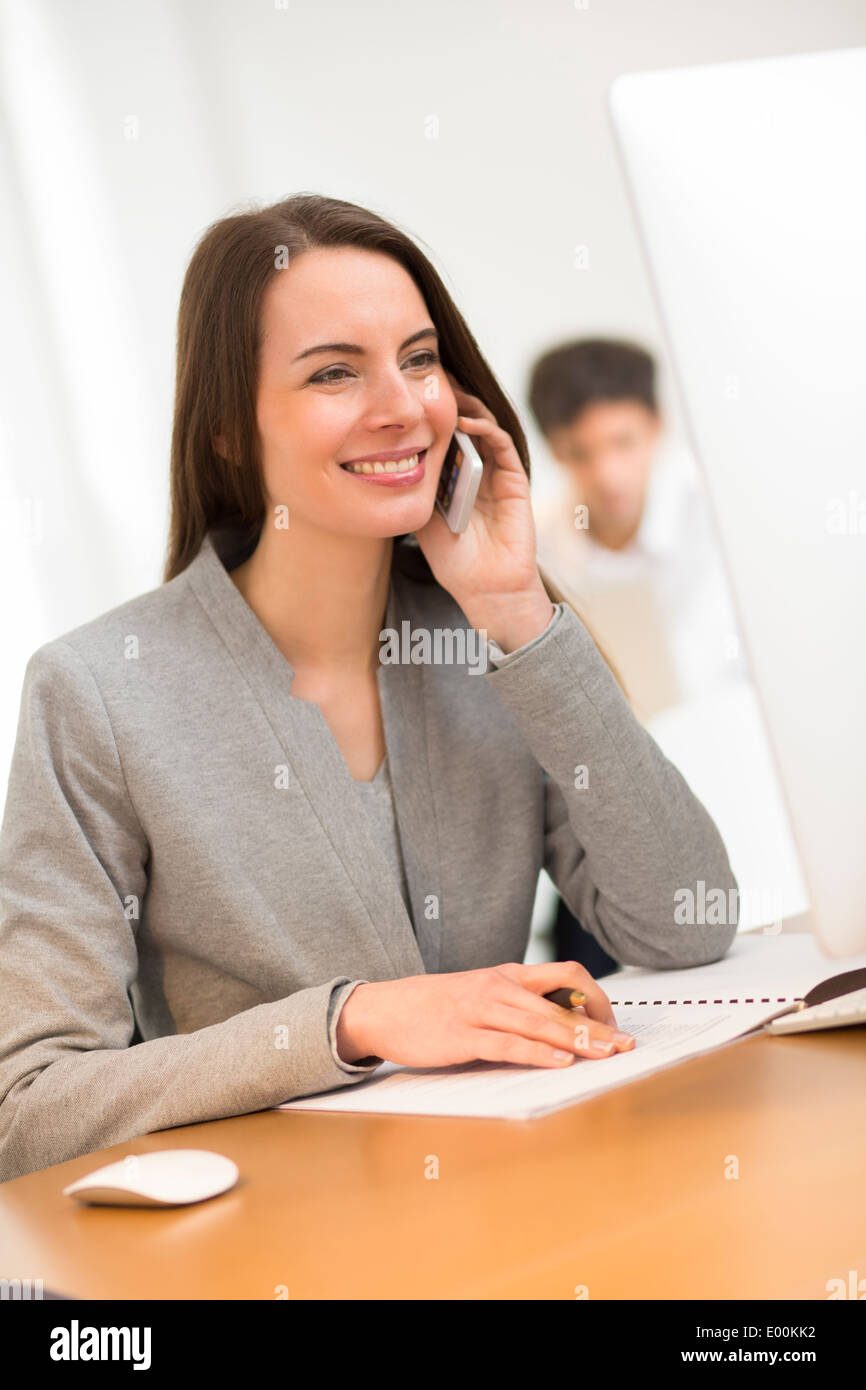 lächelnde weibliche hübsche Smartphone-Schreibtisch-computer Stockfoto