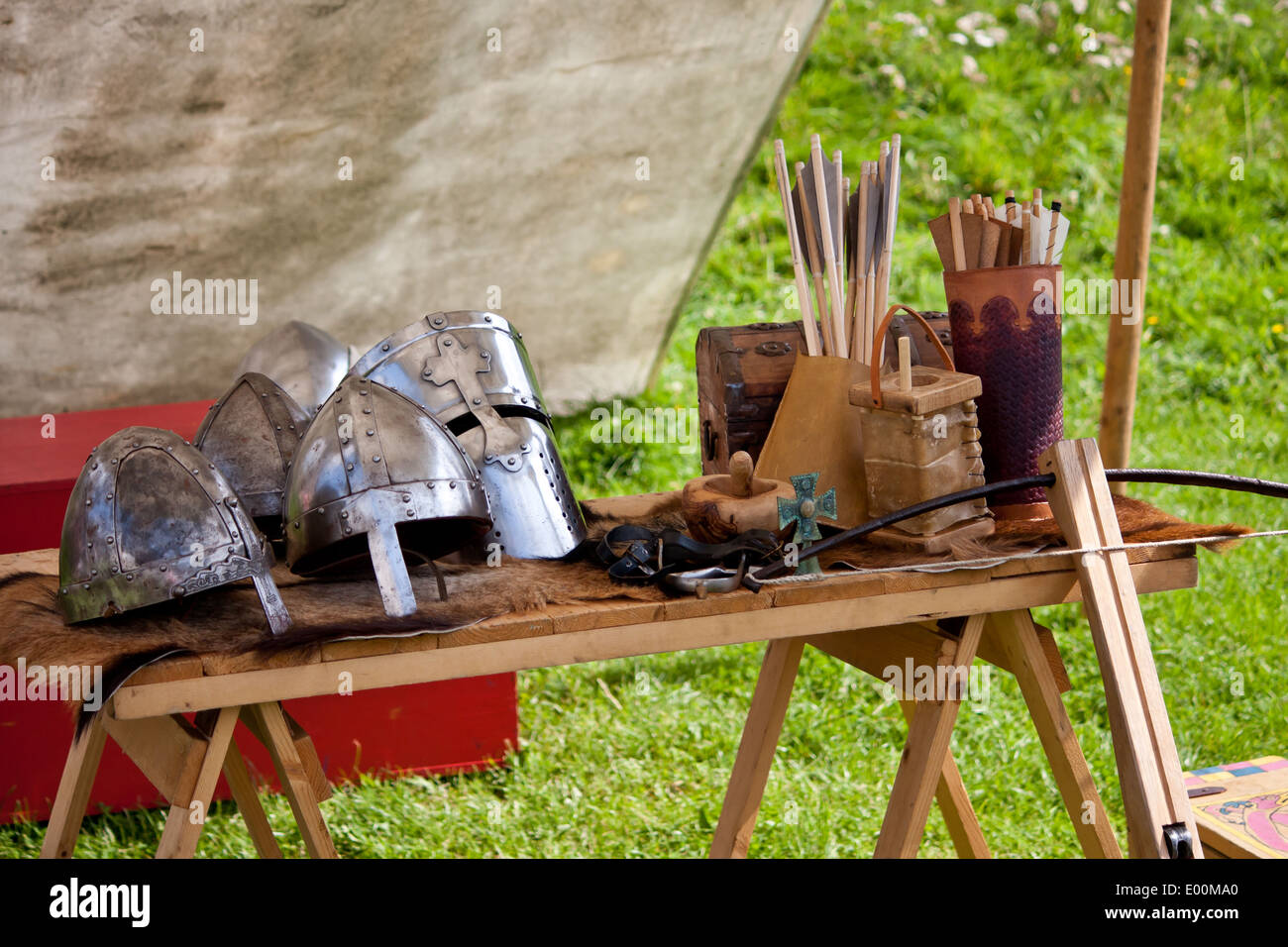 Eine Tabelle mit historischen Instrumenten des Krieges aus einer zivilen Reenactment-Show mit Helmen Rüstung Waffen und vieles mehr. Stockfoto