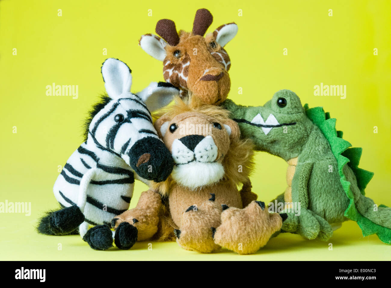 Vier niedlich und kuschelig afrikanischen Stofftier Tiere beisammen sitzen. Ein Löwe, ein Zebra, eine Giraffe und ein Krokodil zusammengekauert. Stockfoto