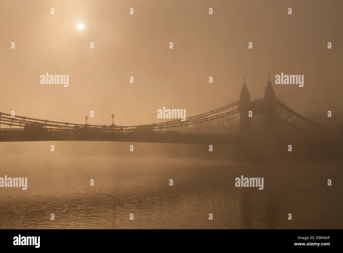 Hammersmith Suspension Bridge eingehüllt in sehr dichten Nebel am frühen Morgen mit der Sonne glühenden durch den Nebel Stockfoto