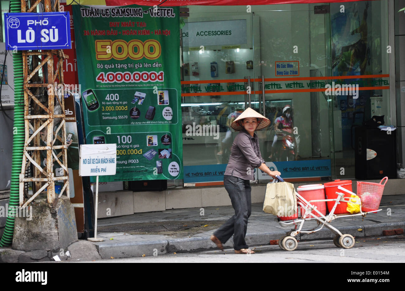 Ein Straßenhändler Frau schiebt einen Wagen im Zentrum von Hanoi, die Hauptstadt von Vietnam Stockfoto