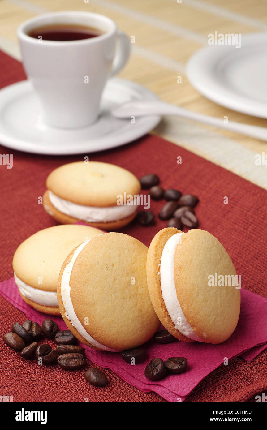 Cookies mit Marshmallows und Tasse Kaffee auf einer roten Tischdecke Stockfoto