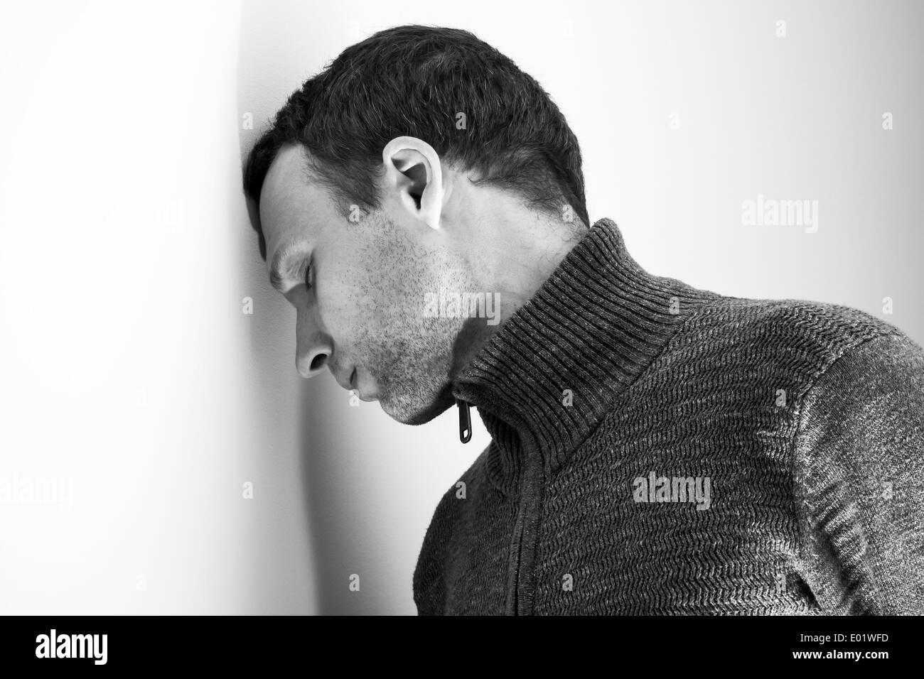 Traurig kaukasischen Jüngling legte seinen Kopf auf weiße Wand Stockfoto