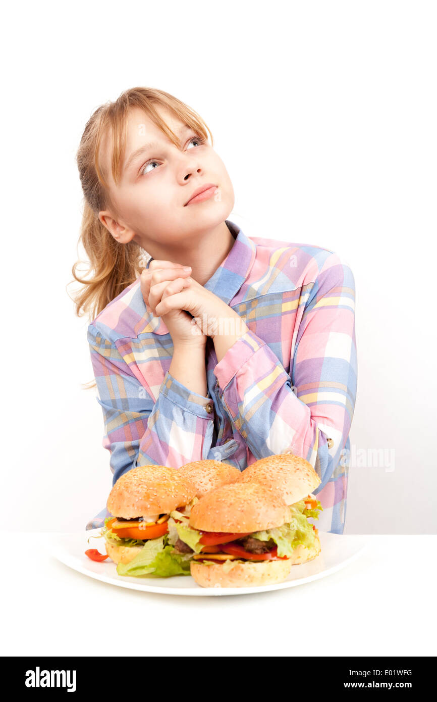 Kleines blondes Mädchen mit großen hausgemachten Hamburgern auf weißen Teller Stockfoto