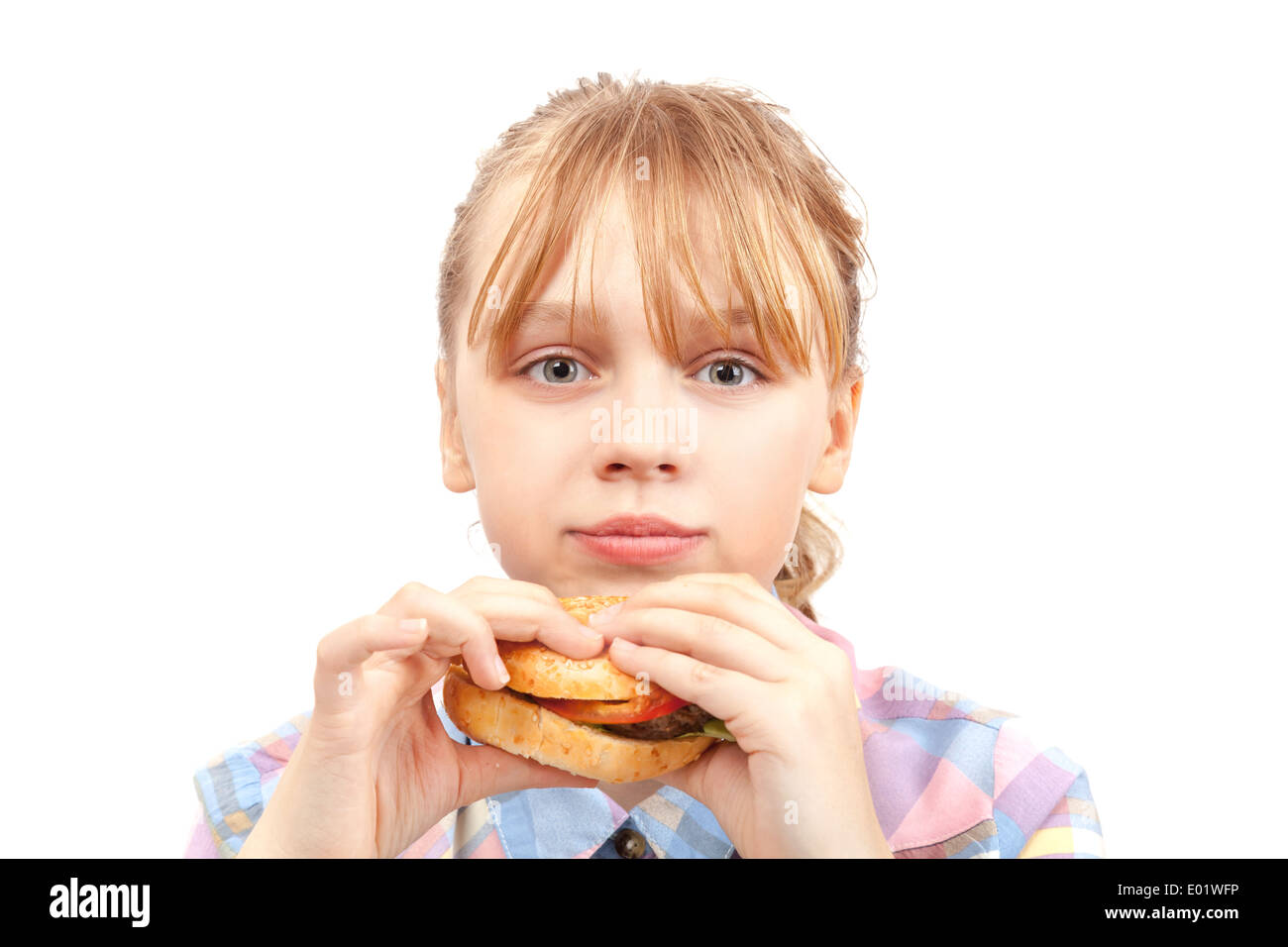 Kleines blondes Mädchen isst Hamburger. Porträt, isoliert auf weiss Stockfoto